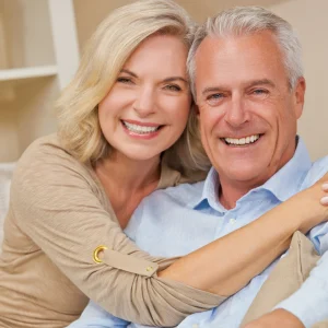 Older couple smiling closely together indoors, cheek to cheek