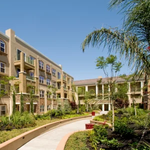 Landscaped courtyard of a multi-story condominium complex with palm trees and walkways