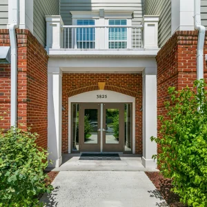 Brick condominium entrance with glass double doors and a street address plaque