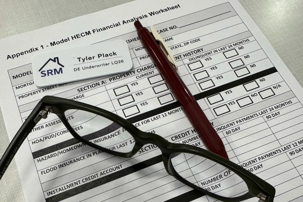 HECM financial analysis worksheet with reading glasses, a pen, and a name badge