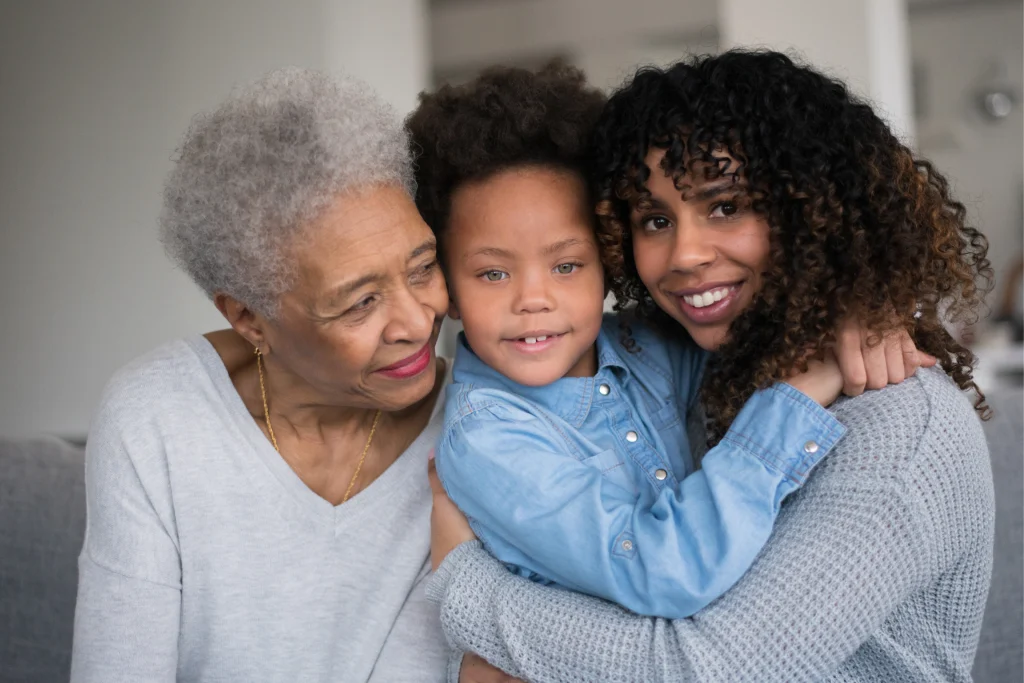 Grandmother embracing her adult daughter and young grandchild at home