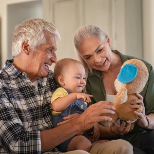 Grandparents playing with a toddler and a stuffed toy on a couch