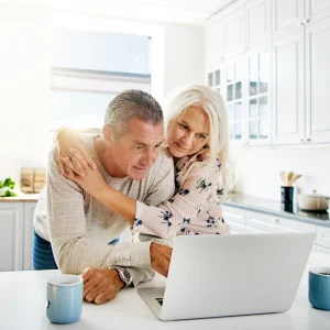 Low Reverse Mortgage Quotes Explained Couple leaning over a laptop together in a bright kitchen with coffee mugs