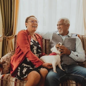 What Happens When a Reverse Mortgage Ends? Couple laughing on a sofa while holding a small dog with a pink collar