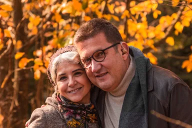 Couple embracing outdoors surrounded by golden autumn leaves