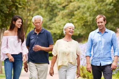 Two generations of a family walking together across a grassy park