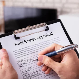 Close-up of a hand filling out a real estate appraisal form on a clipboard