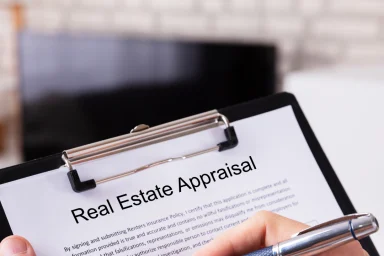 Close-up of a hand filling out a real estate appraisal form on a clipboard