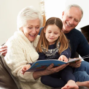 Grandparents reading a picture book together with their granddaughter