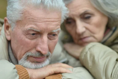 Close-up of a pensive elderly couple leaning their heads together