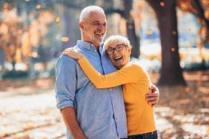 Older couple laughing and embracing outdoors among fall foliage