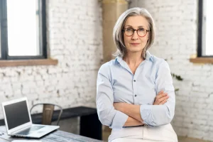 Woman with gray hair standing with arms crossed in a bright office loft