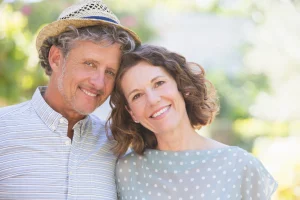 Smiling couple posing together outdoors, the man wearing a straw hat