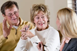 Older couple laughing during a meeting with an advisor, the woman holding her glasses