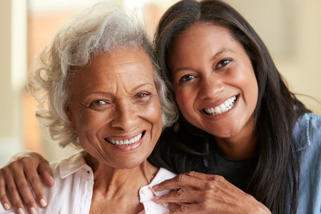 Older woman and younger woman smiling cheek to cheek indoors