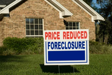Brick house with a yard sign reading Price Reduced Foreclosure