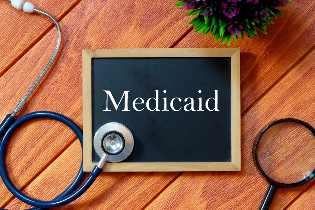Chalkboard sign reading Medicaid next to a stethoscope and magnifying glass