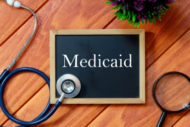 Chalkboard sign reading Medicaid next to a stethoscope and magnifying glass