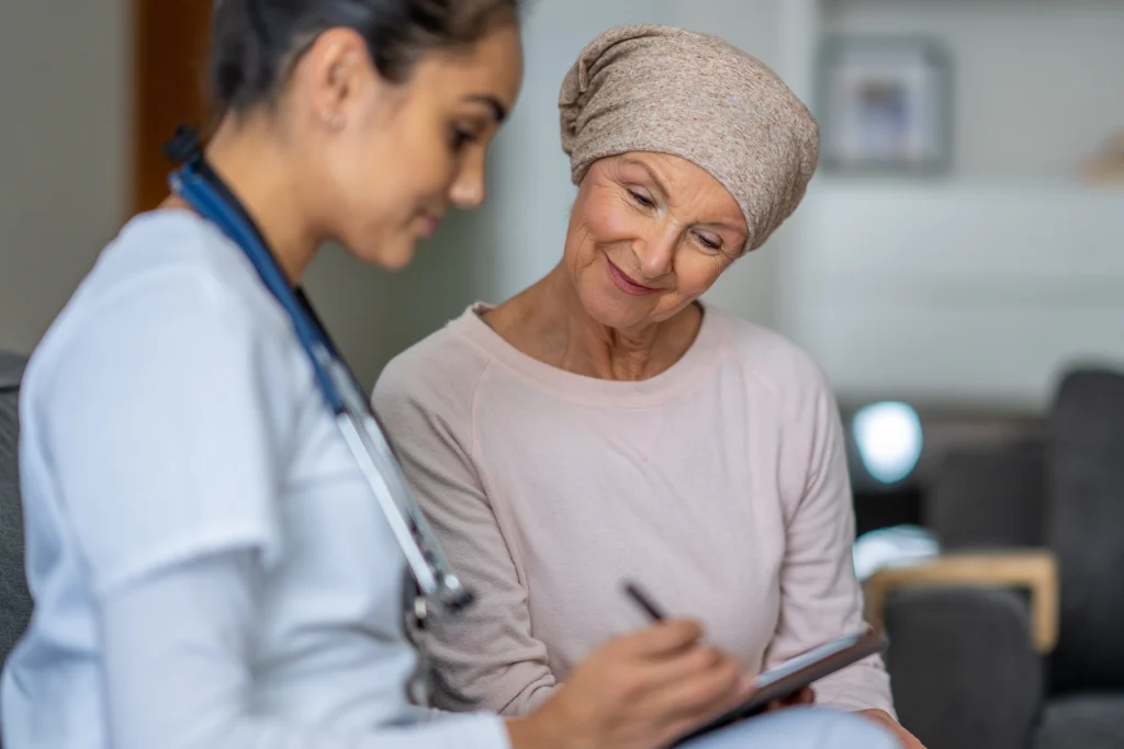 Home health nurse reviewing a tablet with a senior patient wearing a headscarf