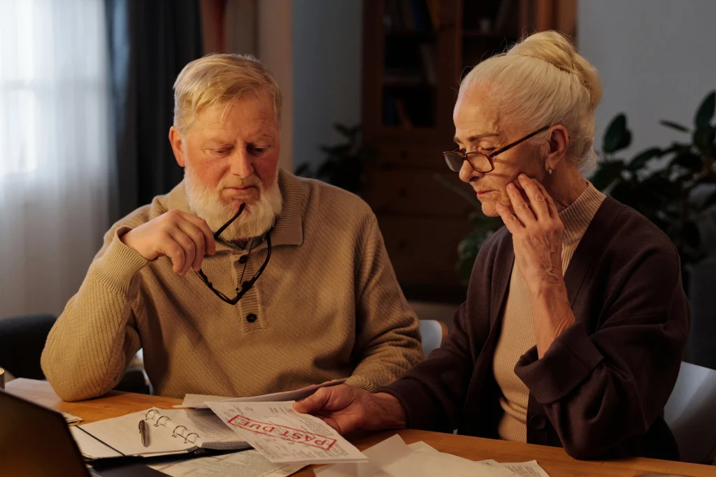 Worried older couple reviewing a past-due bill together at the kitchen table