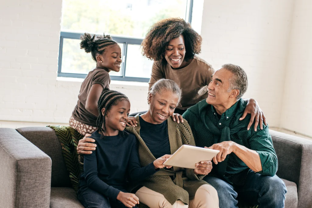 Multigenerational family gathered around a tablet on a couch