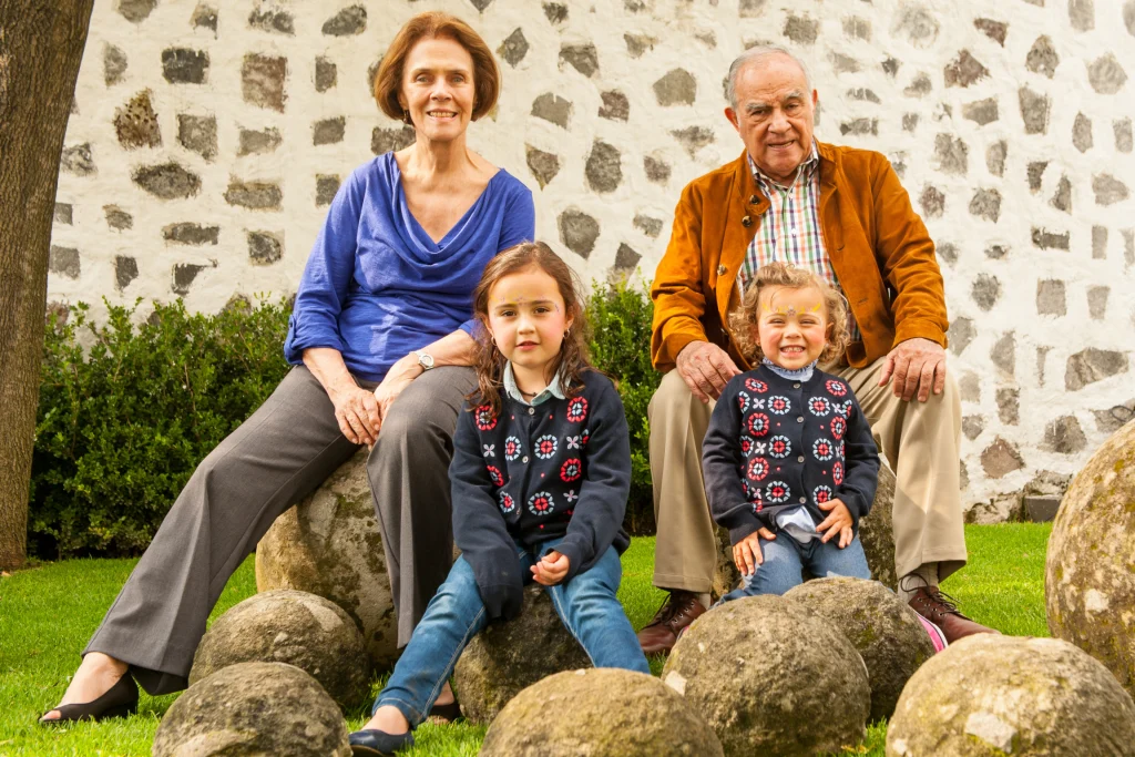Grandparents sitting on garden boulders with two young granddaughters