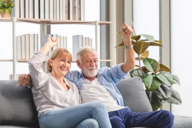 Couple sitting on a couch raising their fists in celebration together