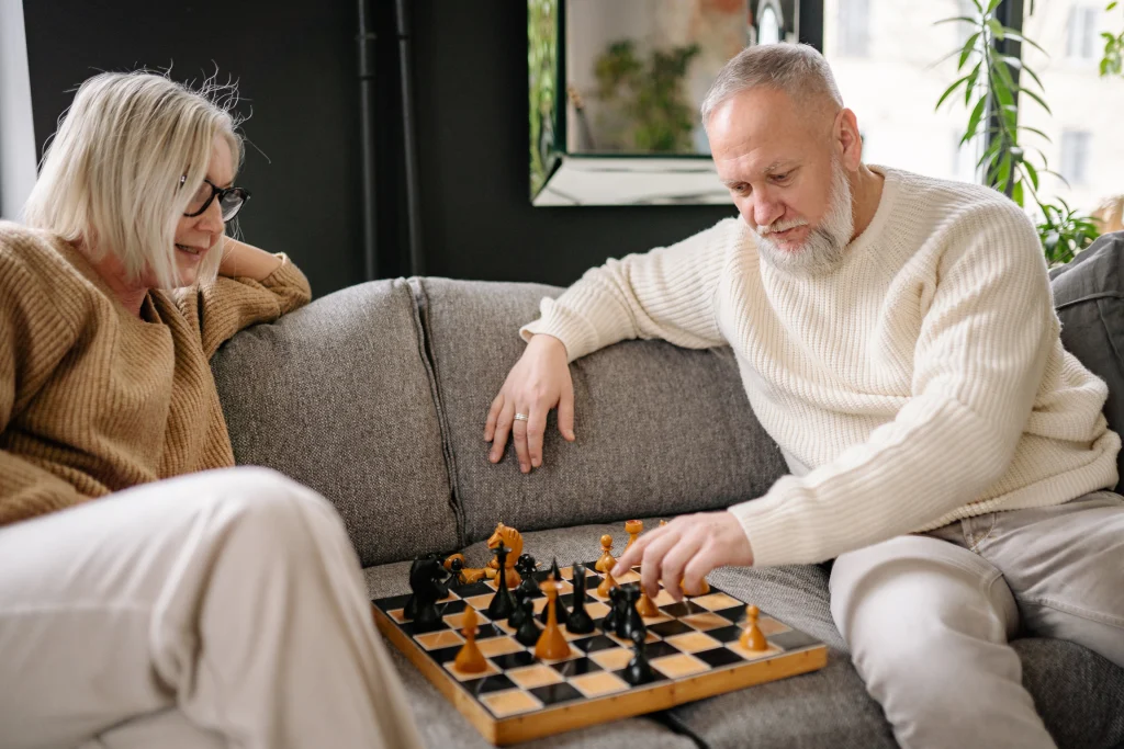 Older couple playing chess together on a living room couch