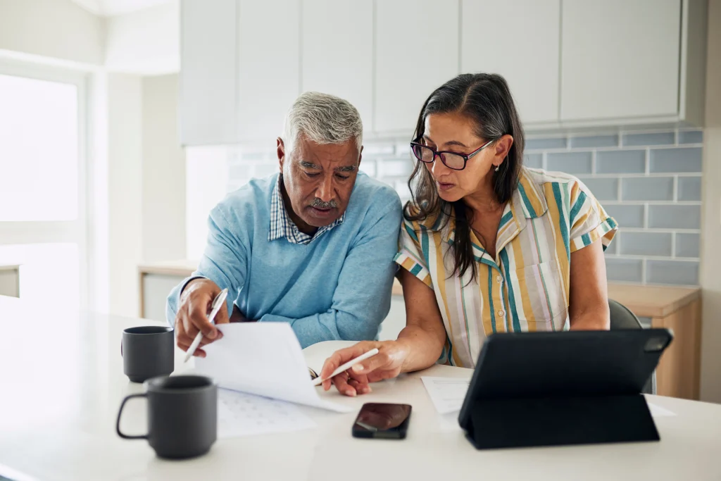 Older couple reviewing documents together at a kitchen counter