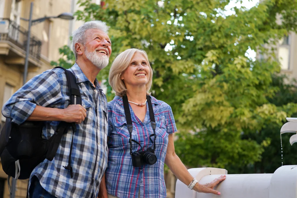 Older couple sightseeing outdoors with a backpack and camera