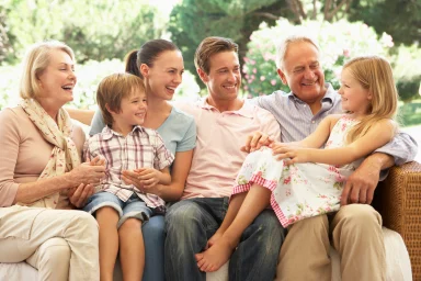 Three generations of a family laughing together on an outdoor sofa