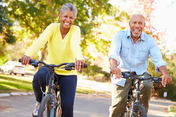 Couple riding bicycles together on a tree-lined path in autumn