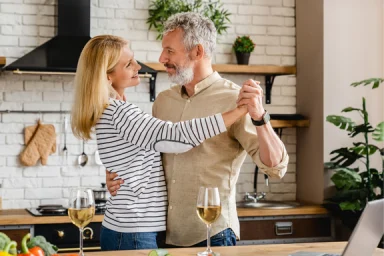 Couple slow dancing in a kitchen while holding wine glasses