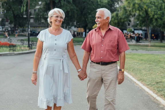 Older couple walking hand in hand along a park path