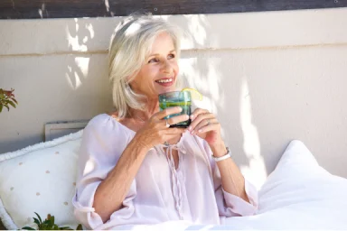 Older woman relaxing outdoors with a cold drink garnished with lemon