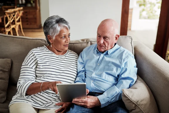 How to tell your kids you’re getting a reverse mortgage. Older couple sitting on a couch looking at a tablet together