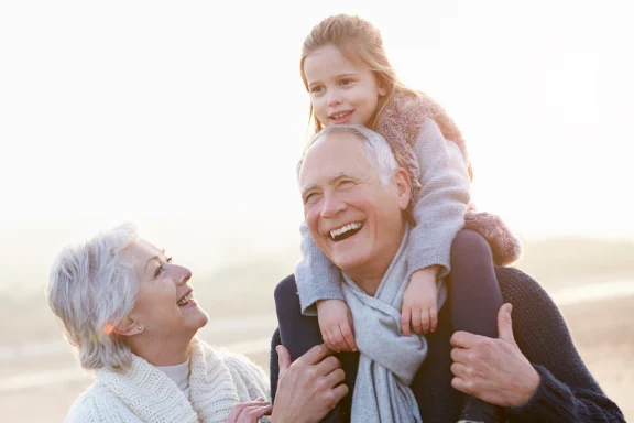 How to tell your kids you’re getting a reverse mortgage. Grandfather carrying a young girl on his shoulders on the beach