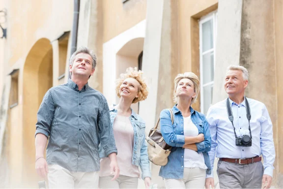 Four adults looking up at old buildings while walking together outdoors