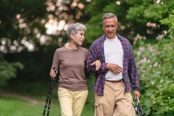 Older couple walking outdoors together using trekking poles